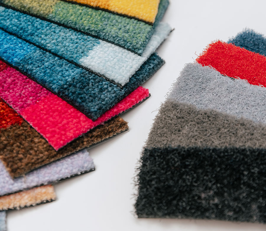 Diversi ritagli di materiale da tappeti di molti colori poggiano su un tavolo disposti a ventaglio.