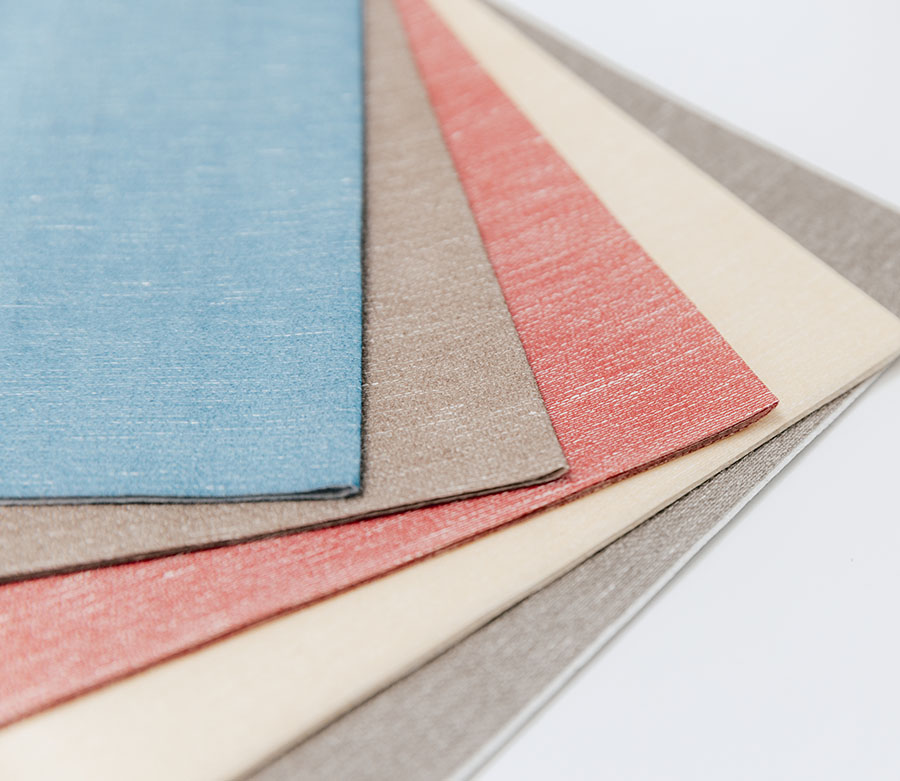 Cinque ritagli di materiale di diversi colori sono poggiati a ventaglio su un tavolo.