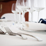 Dettaglio di una tavola apparecchiata con biancheria bianca.