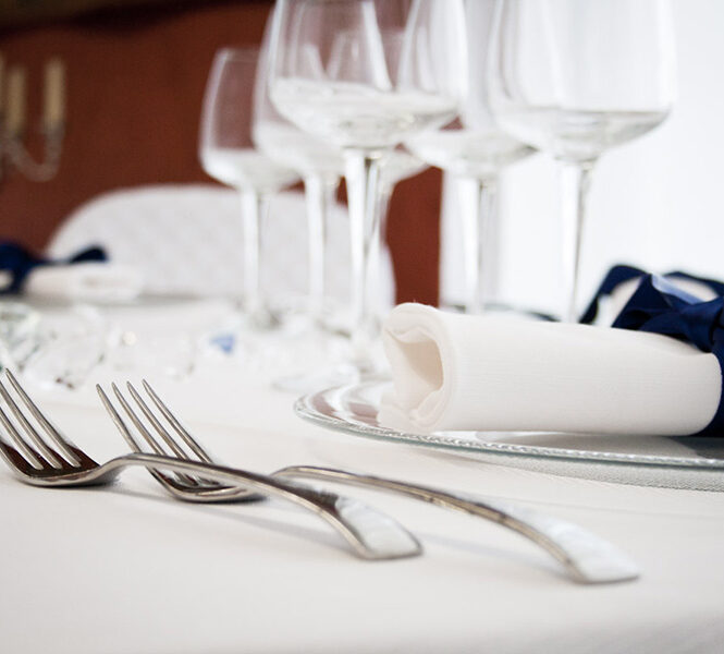 Dettaglio di una tavola apparecchiata con biancheria bianca.