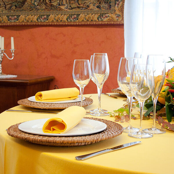 Dettaglio di una tavola apparecchiata con biancheria gialla.