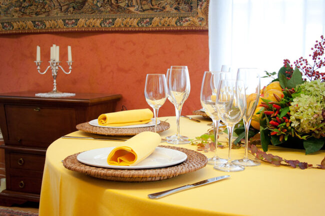 Dettaglio di una tavola apparecchiata con biancheria gialla.
