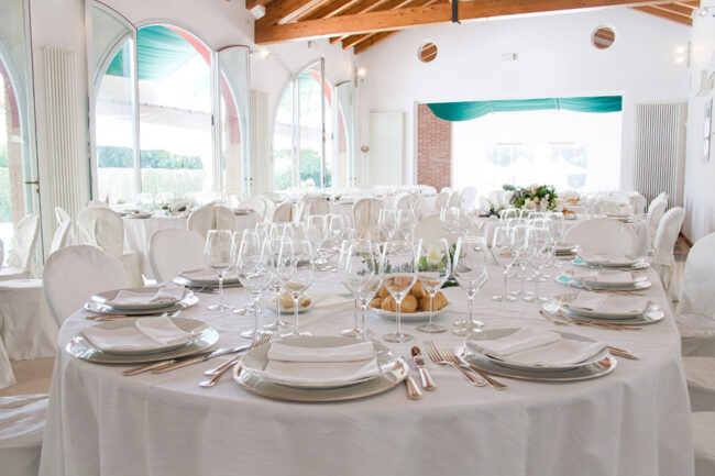 Dettaglio di una tavola apparecchiata con biancheria di lino color bianco.