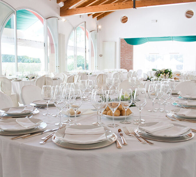 Dettaglio di una tavola apparecchiata con biancheria di lino color bianco.