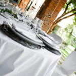 Dettaglio di una tavola apparecchiata con biancheria di lino color bianco.