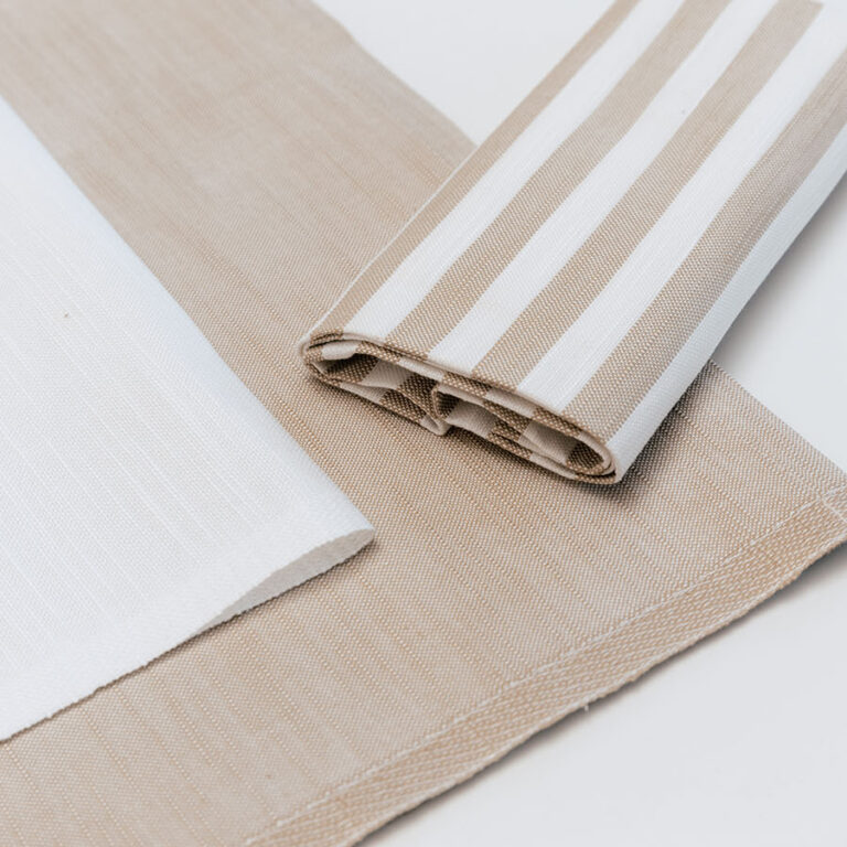 Dettaglio di un tovagliolo a righe marroni e beige posato su una tovaglia.