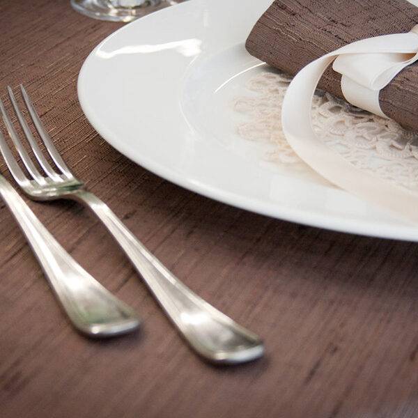 Dettaglio di una tavola apparecchiata con biancheria color marrone.