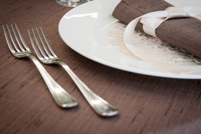 Dettaglio di una tavola apparecchiata con biancheria color marrone.