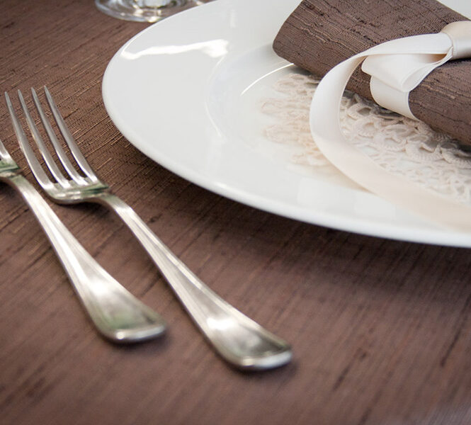 Dettaglio di una tavola apparecchiata con biancheria color marrone.